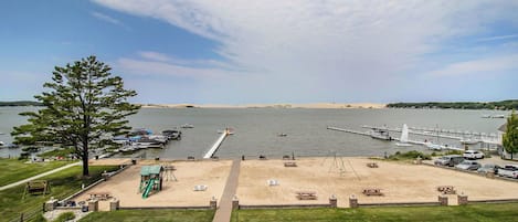 Un parque junto al lago con mesas de picnic, un área de juegos y un muelle que se adentra en el agua.