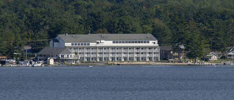 A large, multi-story building with a flat roof, located near a body of water.