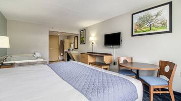 A hotel room with a large bed, a desk with a chair, a television, and a bathroom with a bathtub.