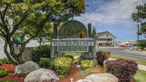 A sign for Dunes Waterfront Resort with a rustic wooden design, surrounded by large rocks and landscaped greenery.