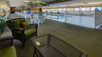 A pool area with lounge chairs and umbrellas, a glass table, and a view of the pool.