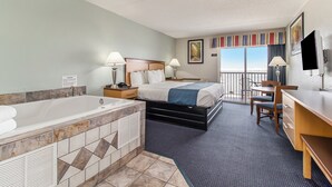 A hotel room with a large bathtub, a bed with two pillows, a desk with a chair, and a television.