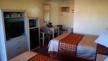 A hotel room with two beds, a desk, a chair, a television, and a microwave.