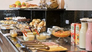 A buffet with various food items, including pastries, fruits, and condiments. - Hotel Renascença (Gramado)