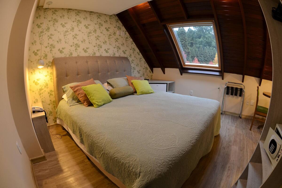 A bedroom with a bed, pillows, a nightstand, a window, and a radiator.