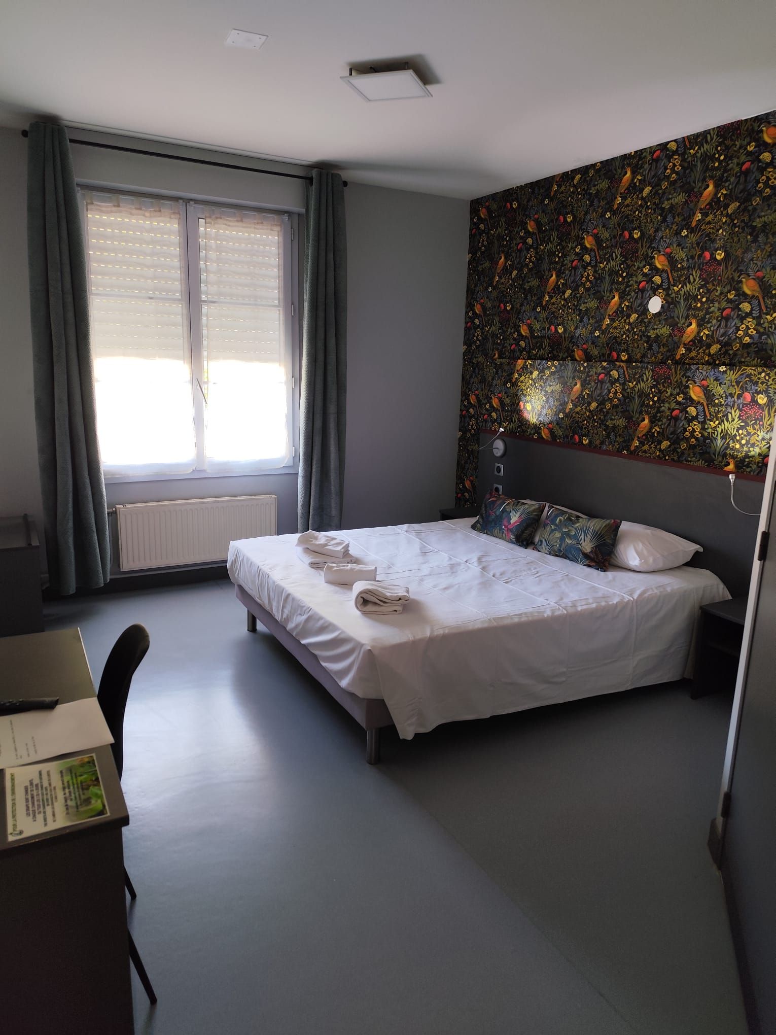 Un dormitorio con cama, escritorio y ventana con cortinas.