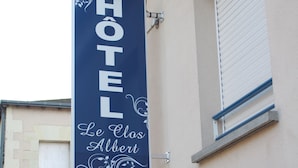Une enseigne d’hôtel portant le nom « HÔTEL Le Clos Albert », fixée sur un poteau.