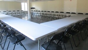 Une salle de conférence avec une longue table et des chaises, un tableau blanc et une porte.