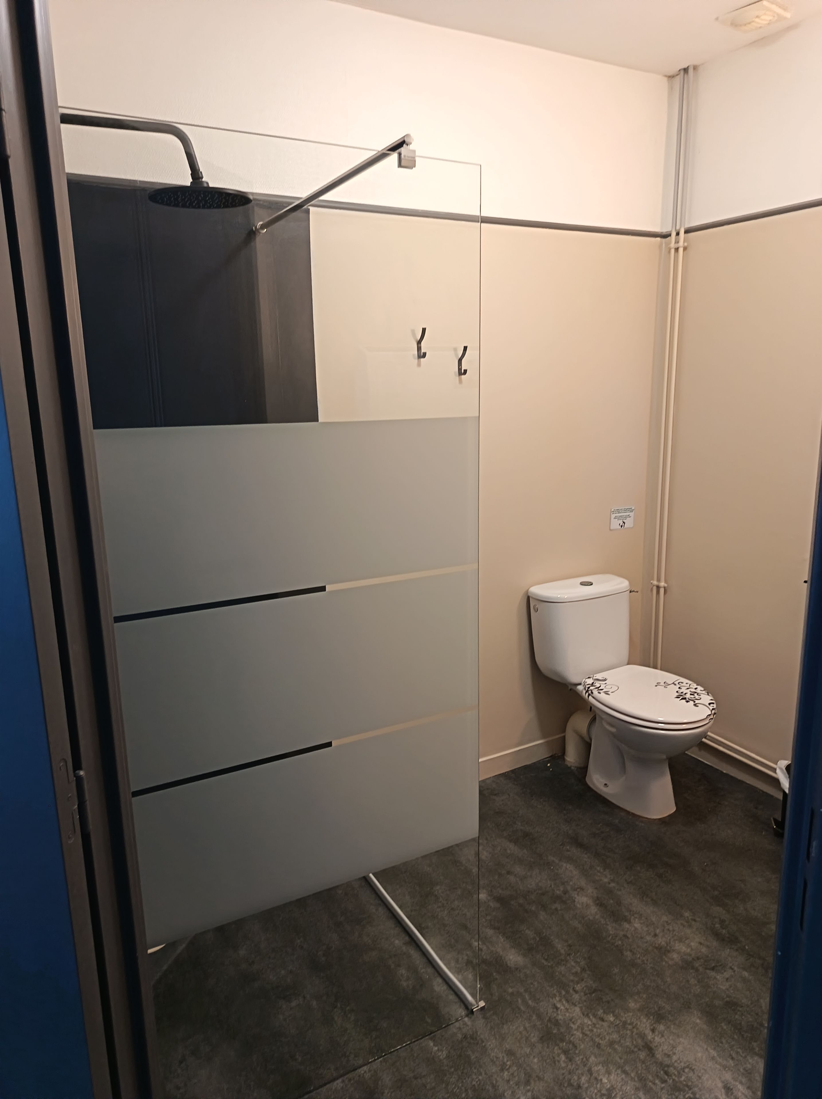 Une salle de bain comprenant des toilettes, un espace douche et un meuble de rangement.