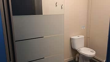Une salle de bain comprenant des toilettes, un espace douche et un meuble de rangement.