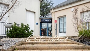 Un bâtiment doté d’un espace d’accueil, d’un escalier menant à l’entrée et d’un panneau indiquant une entrée accessible aux personnes handicapées.