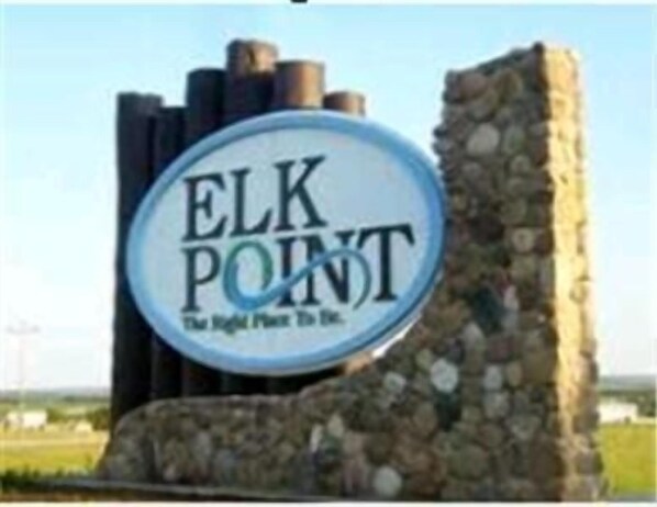 A sign with the text "ELK POINT" and "The Right Place To Be" against a stone structure backdrop.