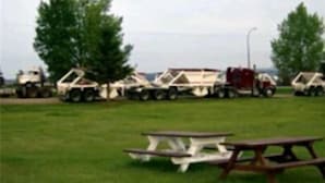 A grassy field with picnic tables and several trucks parked in the background. - Elk Point Motel & RV Park (Elk Point)