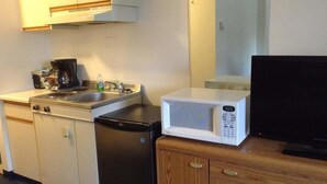 Una kitchenette compacta con estufa, microondas y refrigerador.