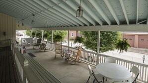 A covered outdoor area with a table, chairs, and a rocking chair. - Sugarcreek Village Inn (Sugarcreek)