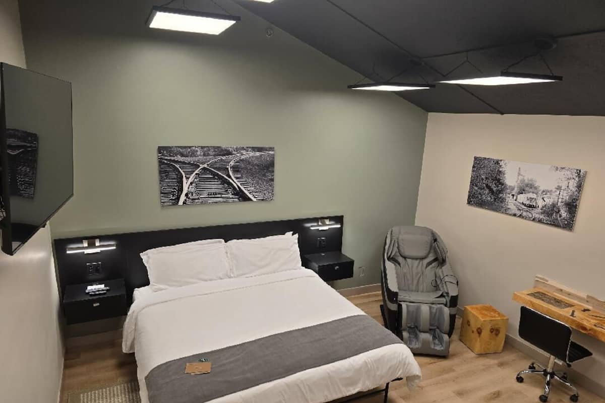 Un dormitorio moderno con una cama grande, mesitas de noche, un escritorio y dos obras de arte colgadas en la pared.