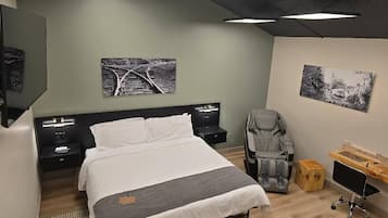 A modern bedroom with a large bed, bedside tables, a desk, and two wall-mounted artworks.