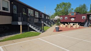 A building with a staircase leading to a deck, a train car labeled "Victoria Station," and a parking area with marked spaces. - Sugarcreek Village Inn (Sugarcreek)