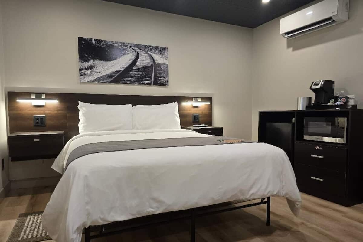 Habitación de hotel moderna con una cama grande, lámparas de noche, un televisor de pantalla plana y un aire acondicionado de pared.