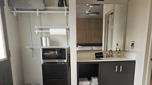 A compact kitchen with a built-in oven, a small refrigerator, and a microwave. There is a trash bin and a black mat near the door. - Sugarcreek Village Inn (Sugarcreek)