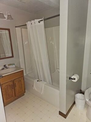 A bathroom with a shower, toilet, sink, and mirror. - Sugarcreek Village Inn (Sugarcreek)