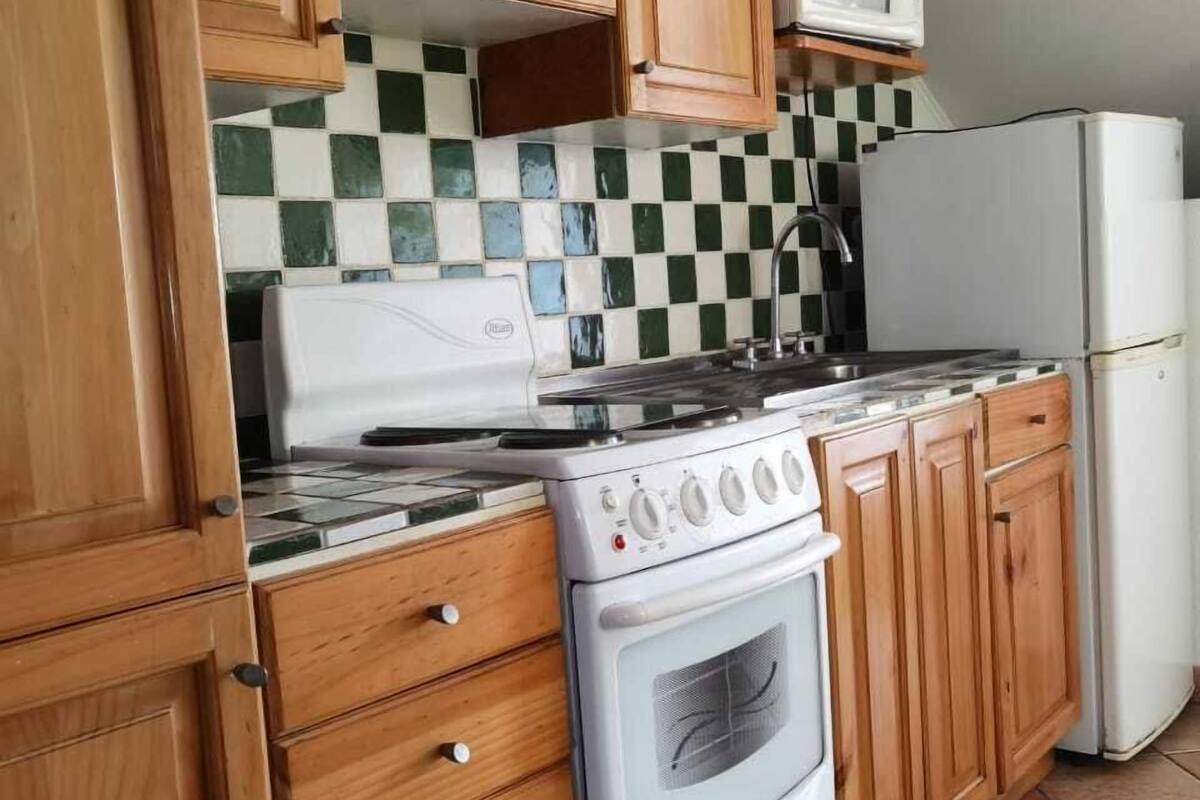 A kitchen with wooden cabinets, a white stove, a microwave, and a refrigerator.