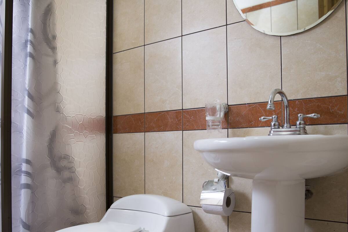 A bathroom with a toilet, sink, and mirror.