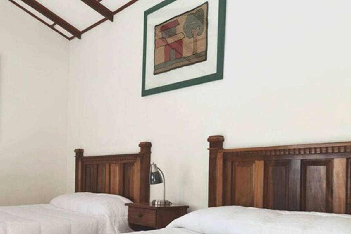 A hotel room with two beds, a nightstand, and a framed picture on the wall.