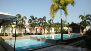 A swimming pool area with multiple pools, palm trees, and umbrellas. - Casa Palmeras Hotel (San Pablo)