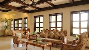 A spacious living room with a high ceiling, large windows, and classic furniture. - Casa Palmeras Hotel (San Pablo)