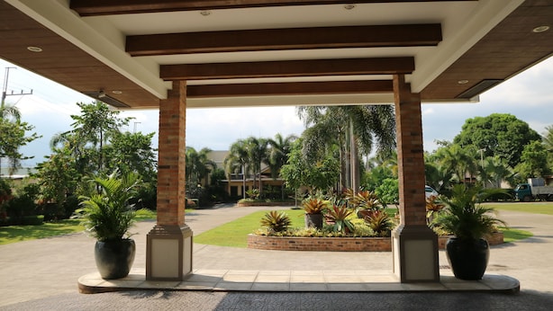 A covered outdoor area with a brick column structure, potted plants, and a paved walkway. - Casa Palmeras Hotel (San Pablo)