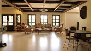 A spacious living room with a high ceiling, large windows, and a dining area. - Casa Palmera Tourist Inn (San Pablo)
