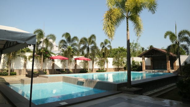 A swimming pool area with multiple pools, palm trees, and umbrellas. - Casa Palmera Tourist Inn (San Pablo)