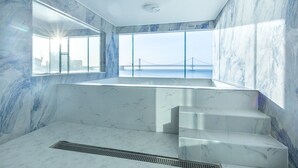Ein modernes Badezimmer mit Marmorwänden, einem großen Fenster mit Blick auf eine Brücke und einer integrierten Duschkabine.