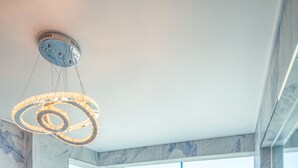 Ein modernes Interieur mit einem Marmortisch und Stühlen, großen Fenstern mit Blick auf das Meer und eine Brücke sowie einer besonderen, runden Leuchte.