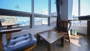 Ein Zimmer mit Blick auf eine Brücke und Gebäude, ein Holztisch, ein Ledersessel und eine kleine Kommode.