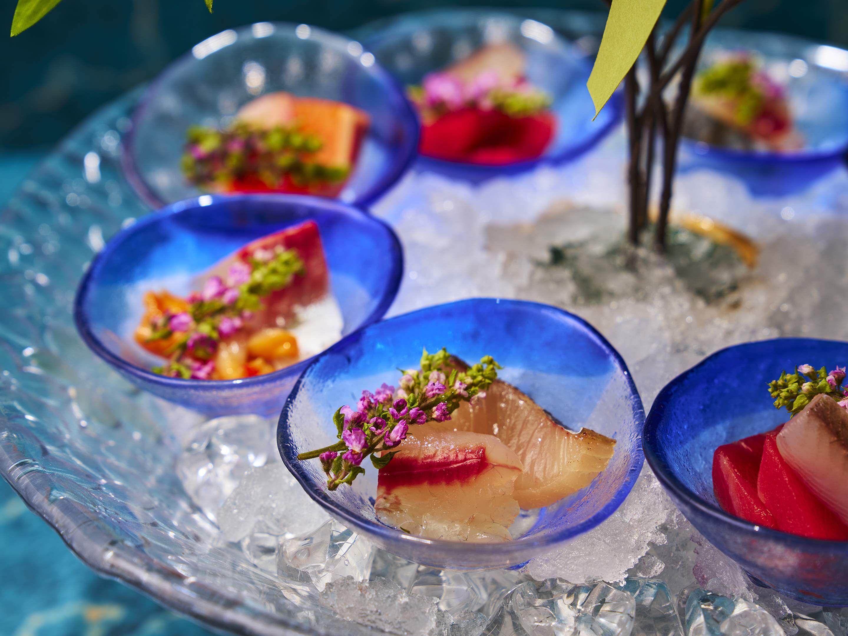 A glass dish with food on ice.