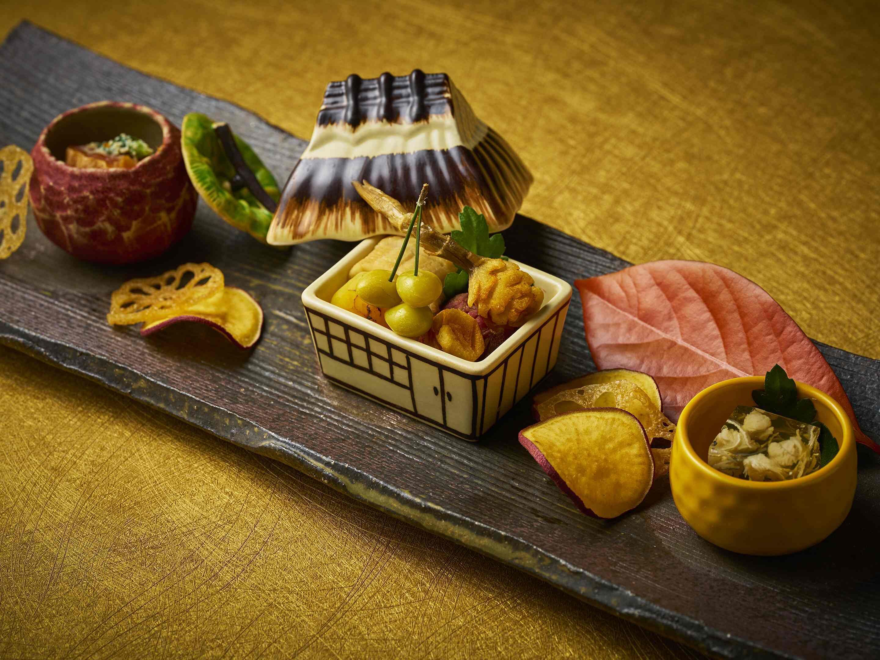 Diverse kleine gerechtjes, mogelijk een Japanse maaltijd, gepresenteerd op een houten plank.