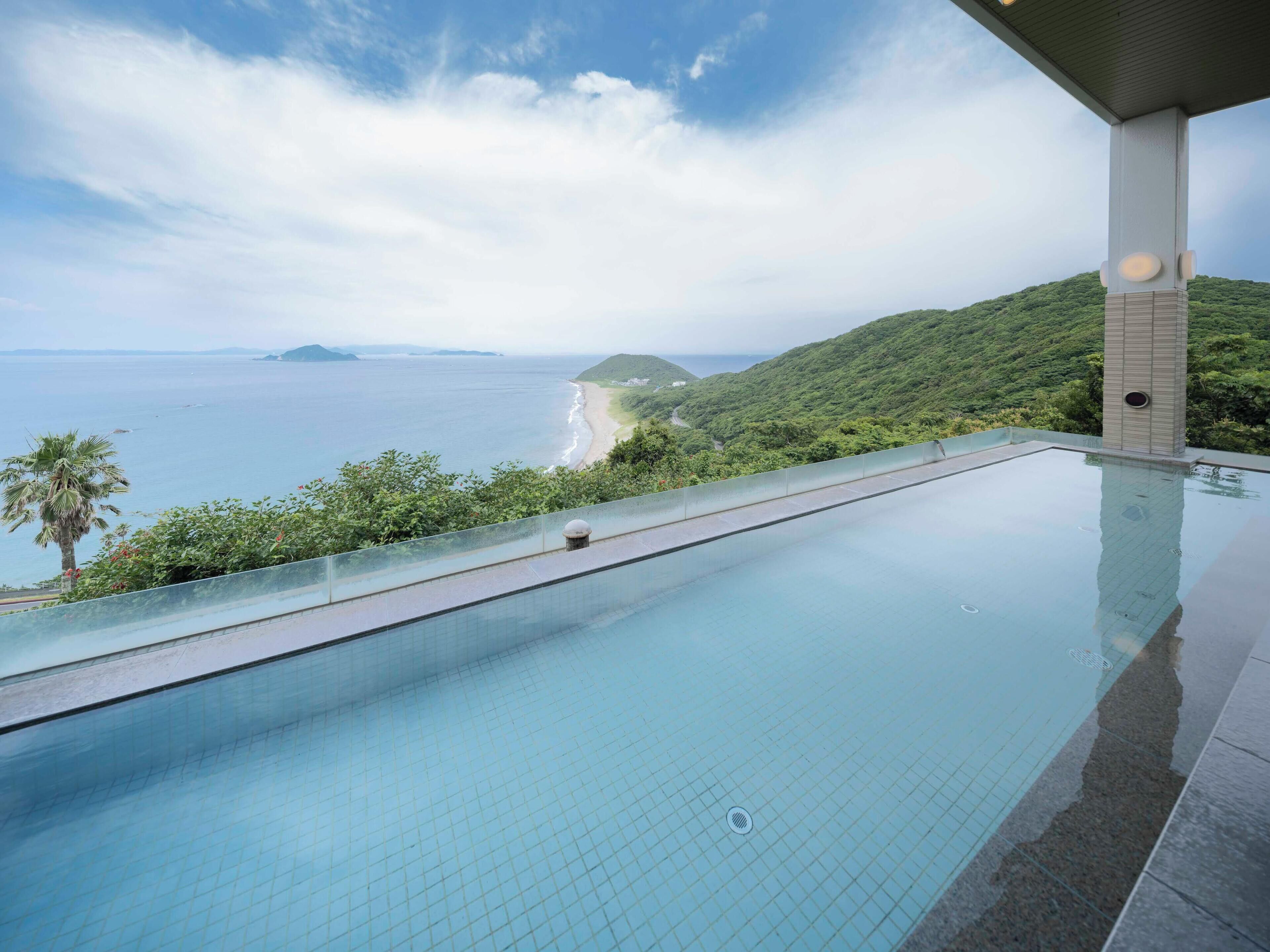 An infinity pool with a clear view of the ocean and a beach.