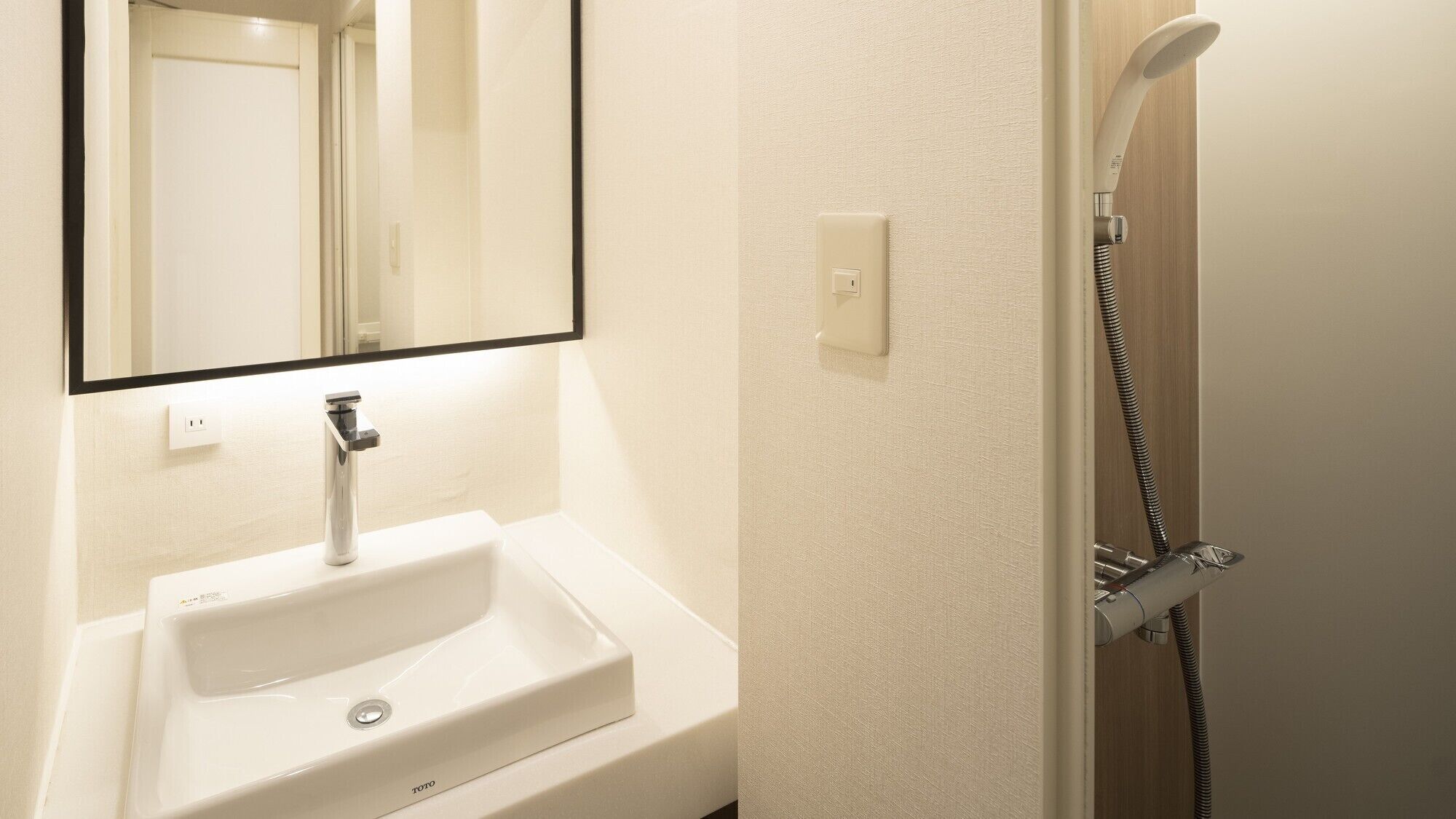 A bathroom with a white sink, a mirror, and a shower.