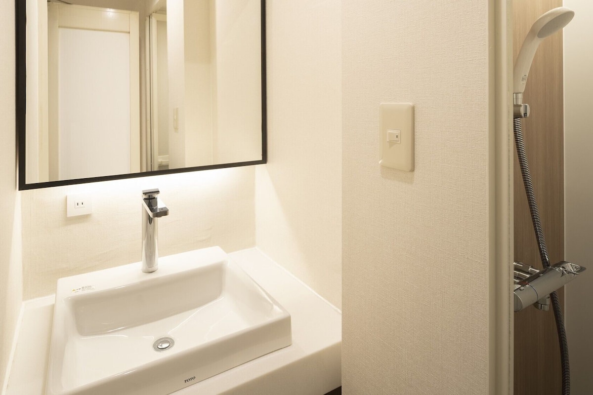 A bathroom with a white sink, a mirror, and a shower.