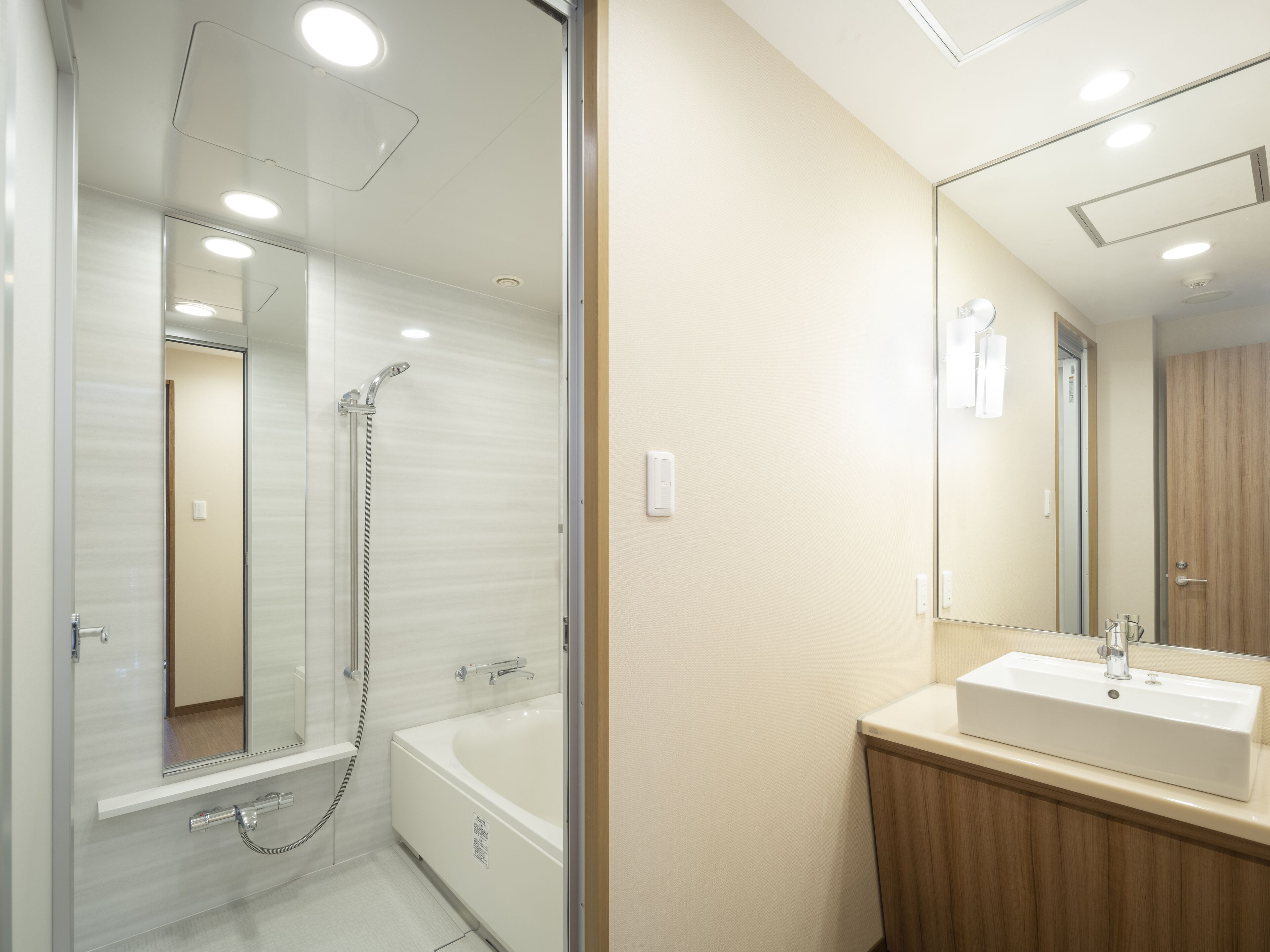 A modern bathroom with a glass-enclosed shower, a white bathtub, and a wooden vanity with a sink.