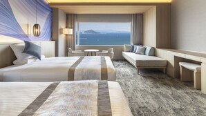 Ein Hotelzimmer mit einem großen Bett, einer Sitzecke, einem Schreibtisch und Meerblick.