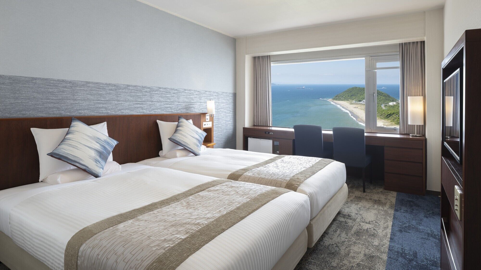 A hotel room with a large bed, a desk, and a view of the ocean.