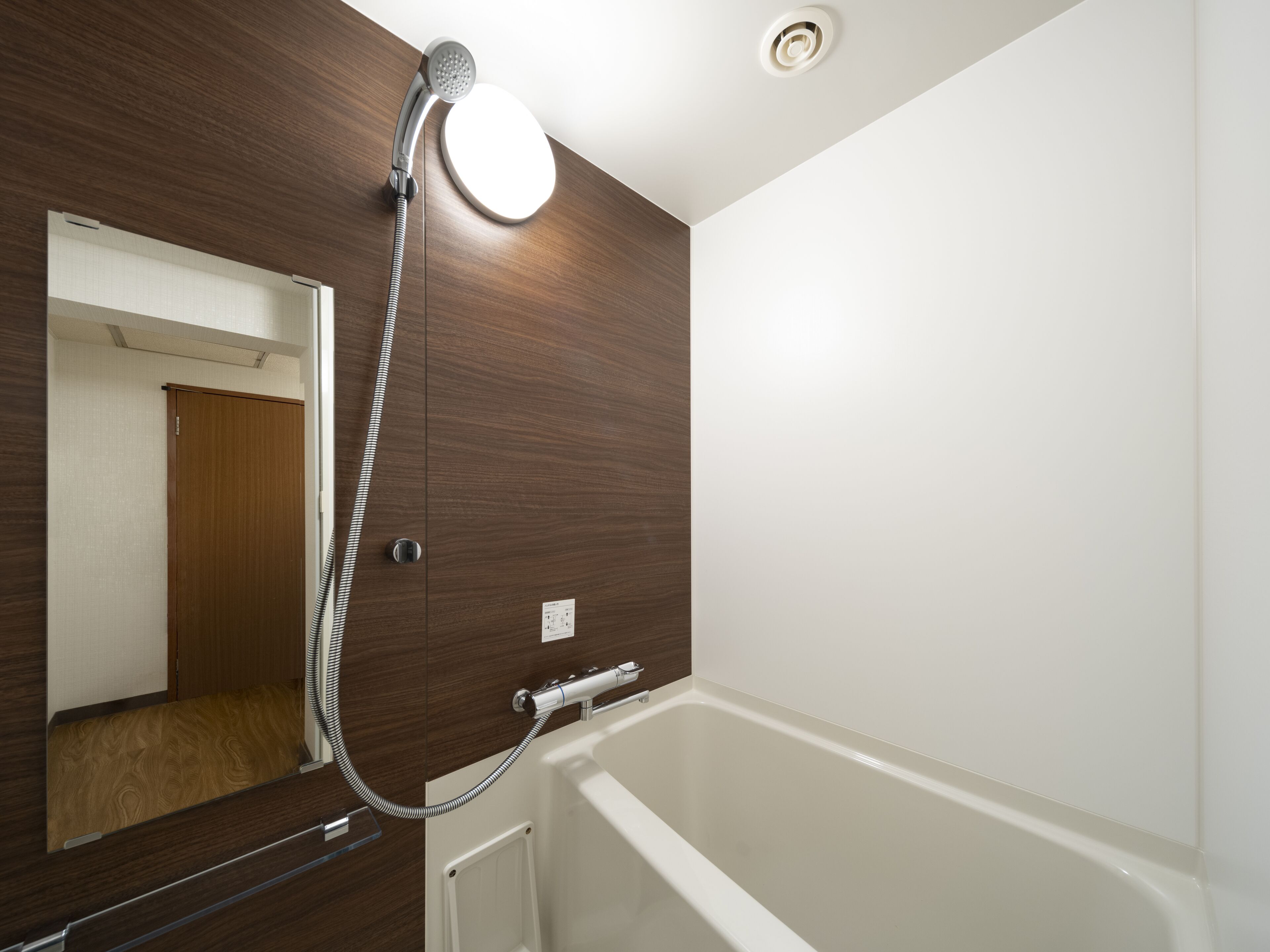A modern bathroom with a wooden vanity, a white bathtub, and a shower head mounted on the wall.
