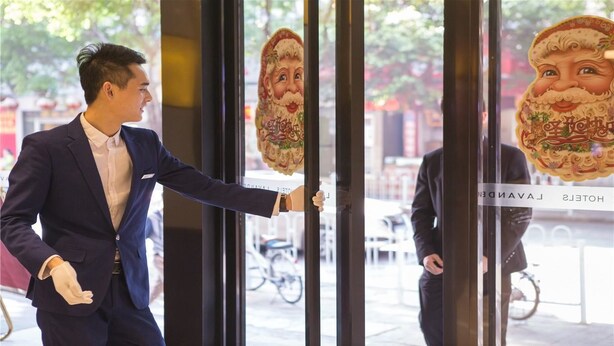 A man in a suit opening a door with a Christmas-themed sticker. - LAVADE HOTEL GZ KECUN METRO STATION BRANCH (Guangzhou)