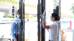 A hotel entrance with a glass door, a person cleaning the glass, and a vehicle outside. - LAVADE HOTEL GZ KECUN METRO STATION BRANCH (Guangzhou)