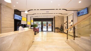 A modern hotel lobby with a reception desk, seating area, and a staircase. - LAVADE HOTEL GZ KECUN METRO STATION BRANCH (Guangzhou)