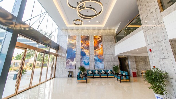A spacious lobby with a modern design, featuring a large seating area, a high ceiling with circular light fixtures, and large windows allowing natural light. - Ease Cloud Hotel (Beijing)