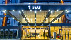 A modern hotel entrance with a glass facade, illuminated signage, and a well-lit interior visible through the doors. - Ease Cloud Hotel (Beijing)